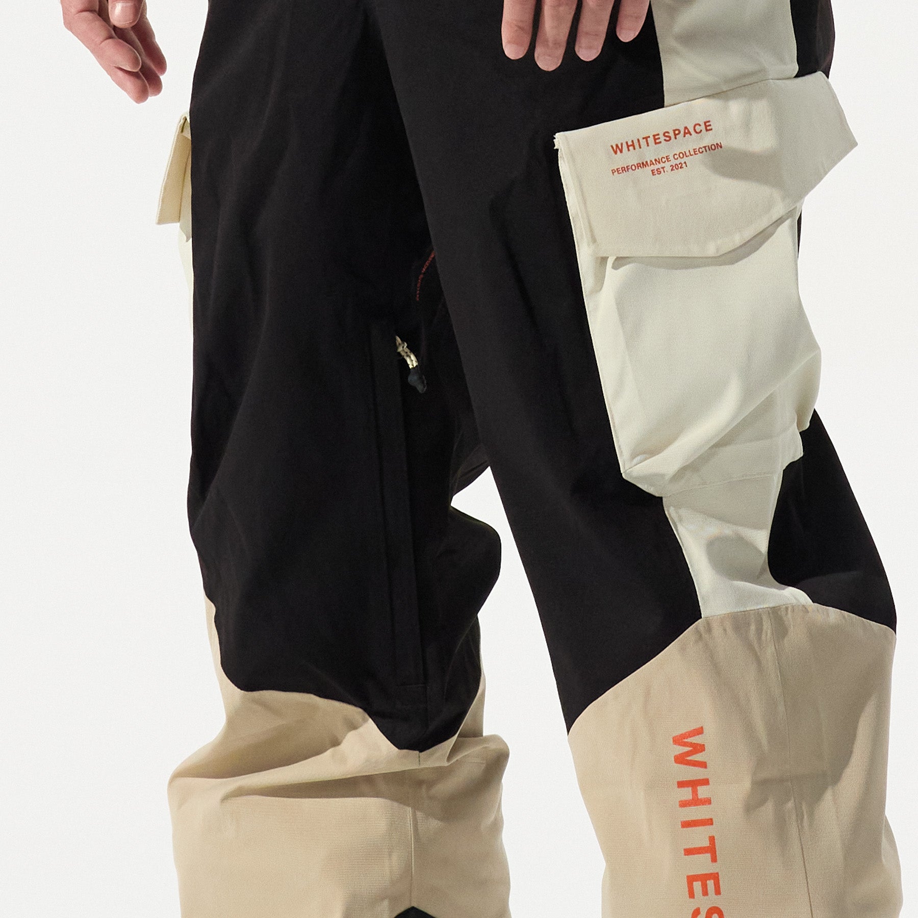 Model wearing black and beige pants with 'Whitespace' branding on a white background