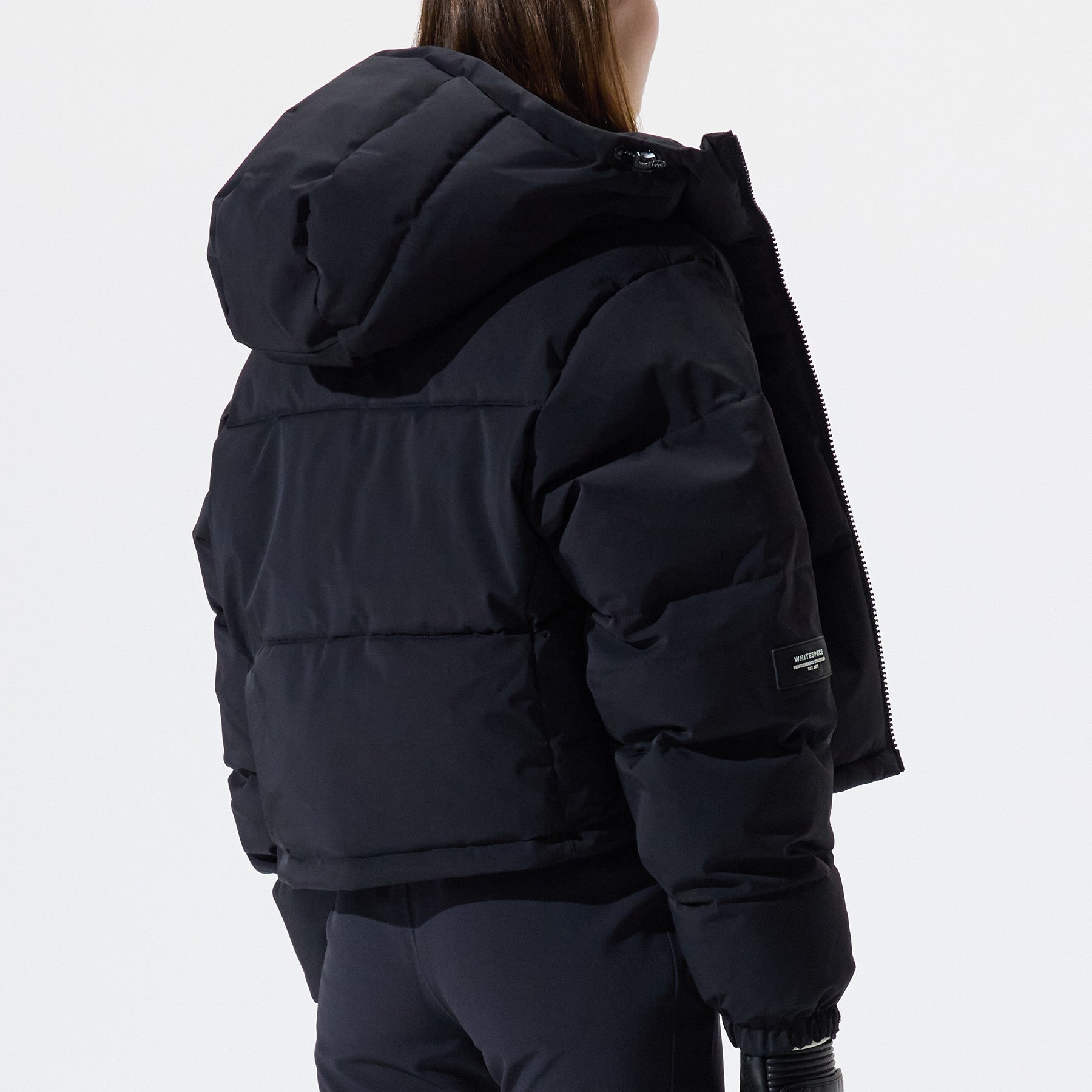 Model wearing Cropped Puffer Jacket in black shown from the back, on a white background.