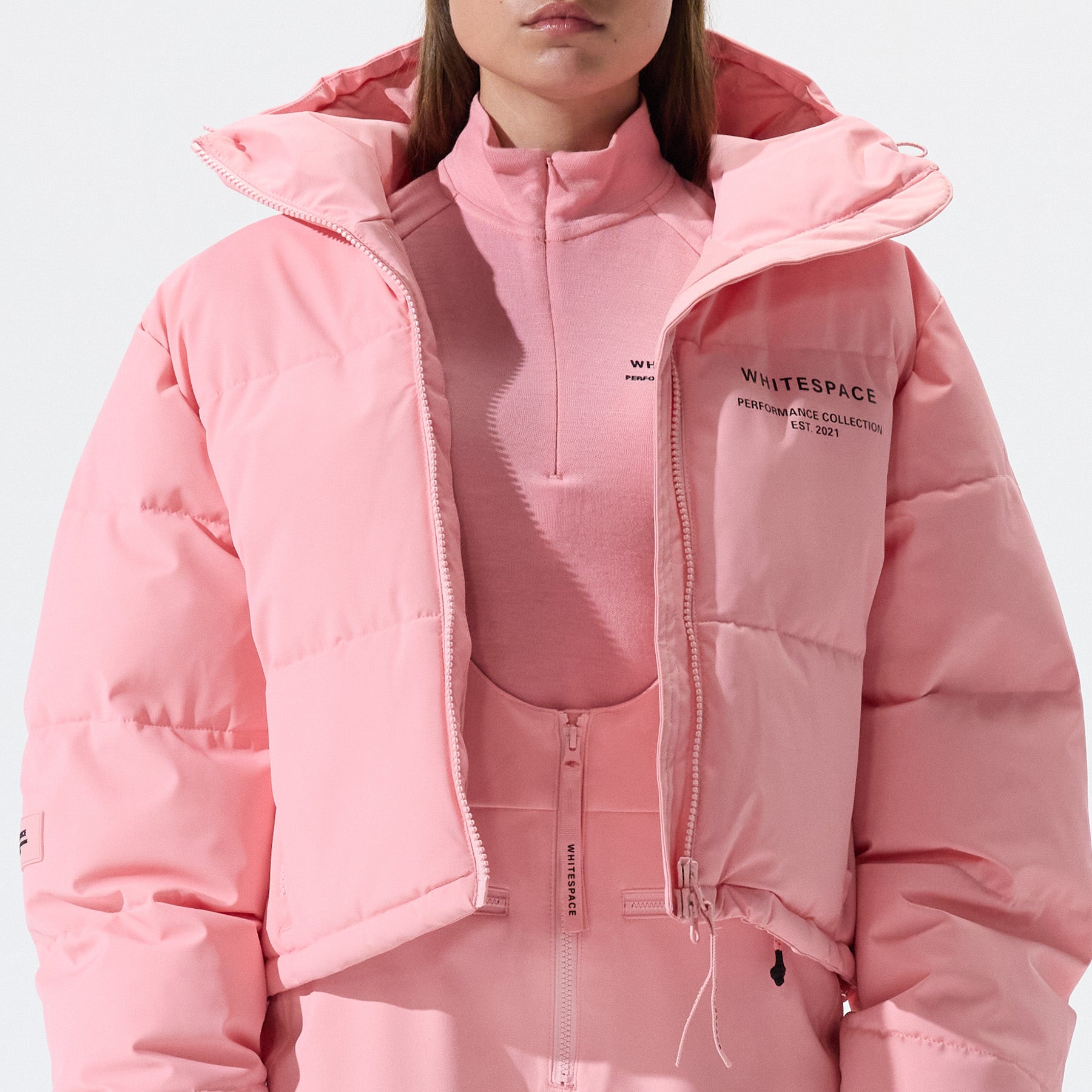 Model wearing Cropped Puffer Jacket in Pink Icing colorway over coordinating pink icing bib snowpants.