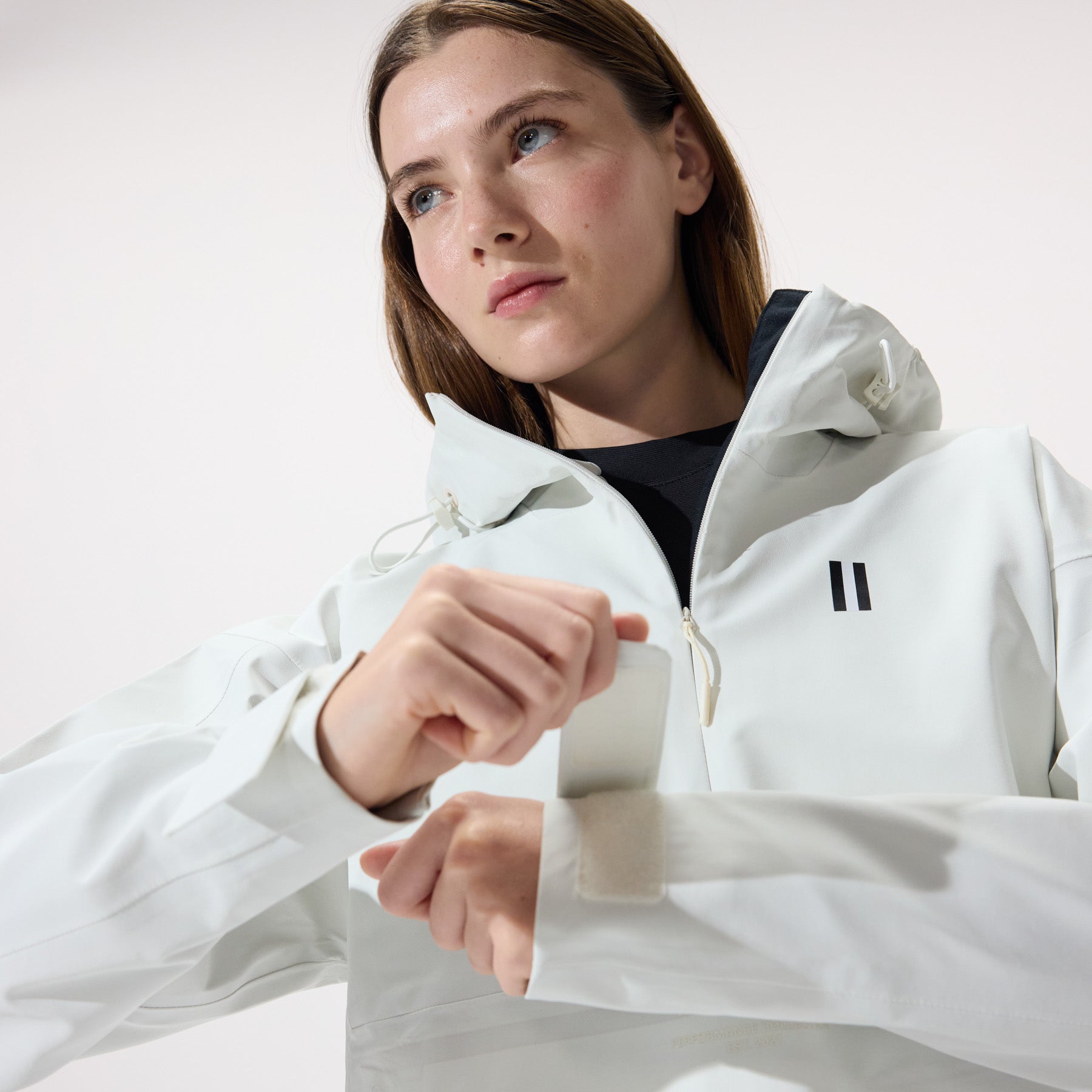 Model wearing a white jacket with a brand logo on a light background