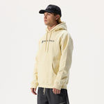 Model wearing Whitespace Block Hoodie in bone, a black Dad Hat, and black pants in front of a white background.