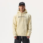 Model wearing Whitespace Block Hoodie in bone, a black Dad Hat, and black pants in front of a white background.