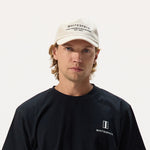 Man wearing a black 'WHITESPACE' shirt and dad hat in bone on a white background.