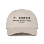 Beige cap with 'WHITESPACE PERFORMANCE COLLECTION EST. 2021' text on a white background