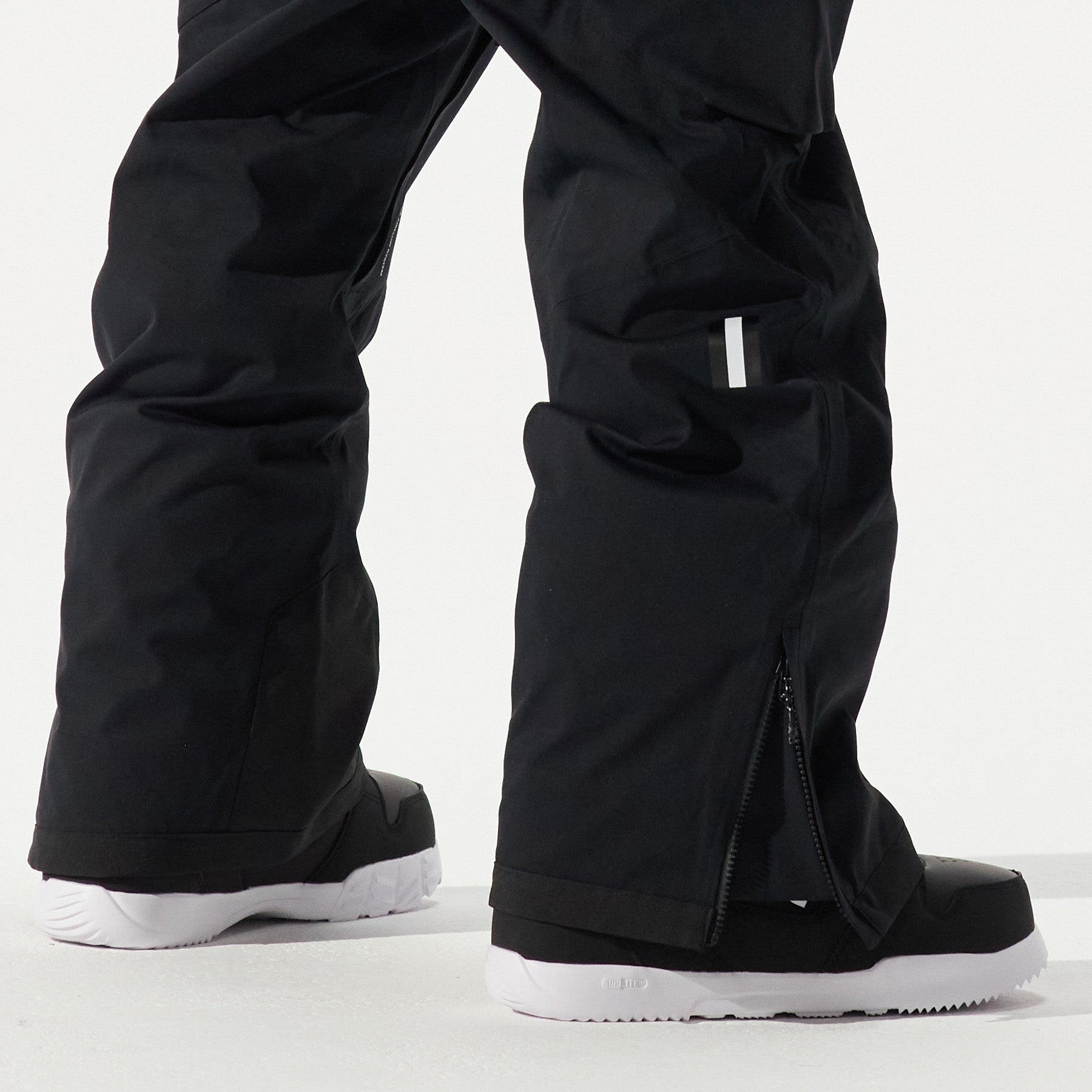 Model shown from the knees down wearing black snow pants and black shoes white soles on a white background