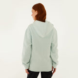 Model, from the back, wearing Farm Rio/ WHITESPACE light blue hoodie and black pants.