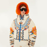 Model wearing Farm Rio Lucy Floral Puffer Jacket, a cream colored jacket with blue and yellow floral designs, coordinating pants, dark sunglasses, and fluffy orange ear muffs, on a white background.