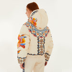 Model, from the back, wearing Farm Rio Lucy Floral Puffer Jacket, a cream colored jacket with blue and yellow floral designs and coordinating pants, on a white background.
