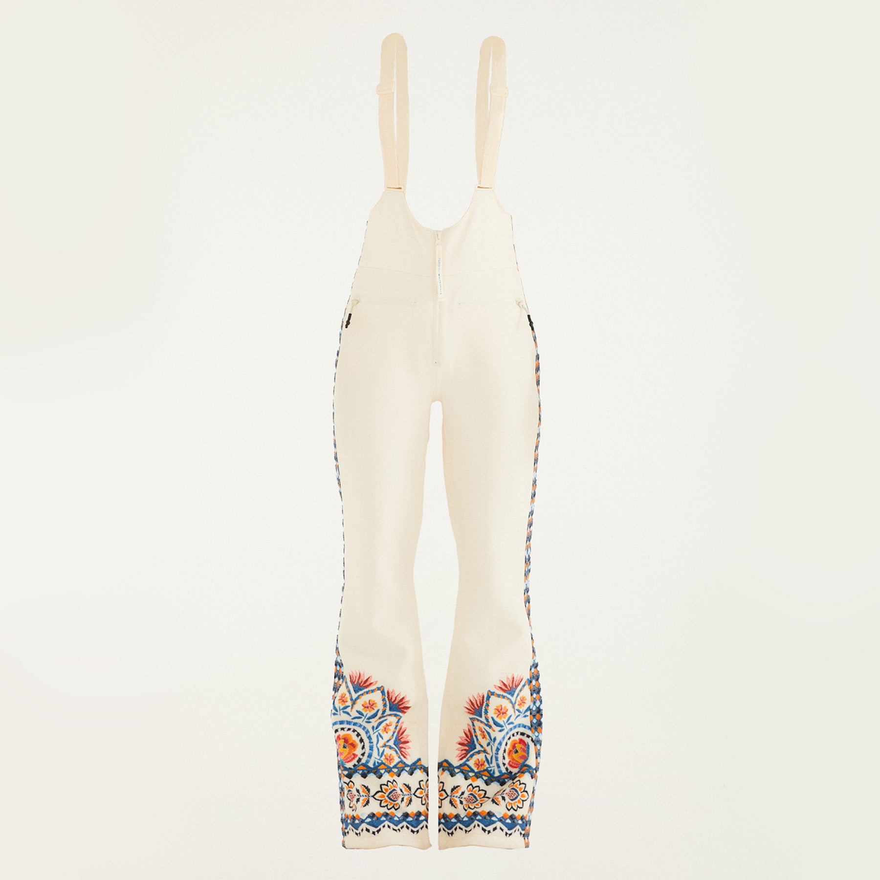 Flat lay of Farm Rio Lucy floral riding bib pants, cream colored bibs with orange and blue floral designs around the bottom of the legs and up the sides to the waist.