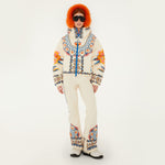 Model wearing Farm Rio Lucy Floral Puffer Jacket and bibs, cream colored jacket and bib with blue and yellow floral designs, white shoes, dark sunglasses, and fluffy orange ear muffs, on a white background