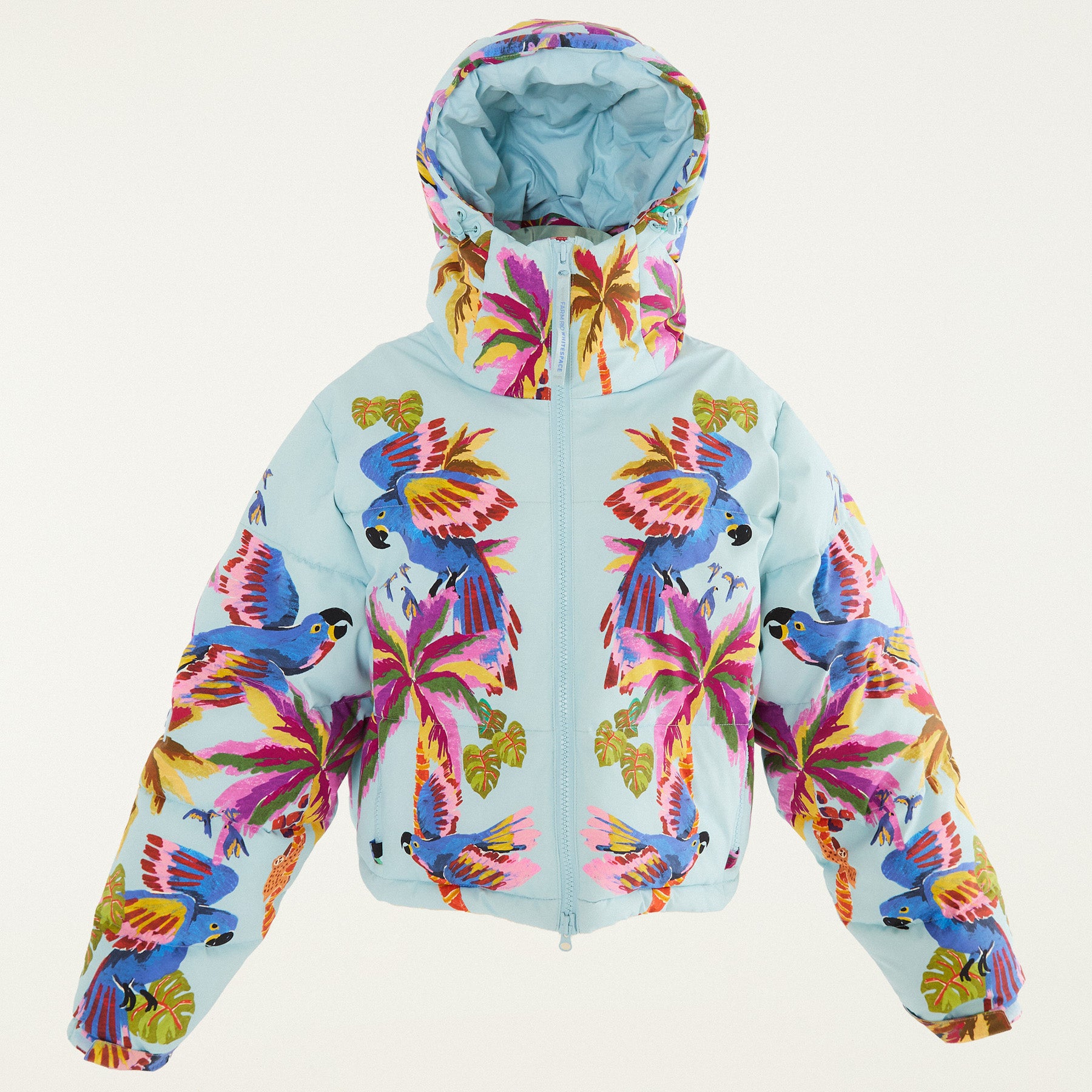 Flat lay photo of Farm Rio Macaw puffer jacket, a light blue jacket with macaw graphic design, on a white background.