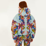Model, from the back, wearing Farm Rio Macaw puffer jacket, a light blue jacket with macaw graphic design and matching pants, on a white background.