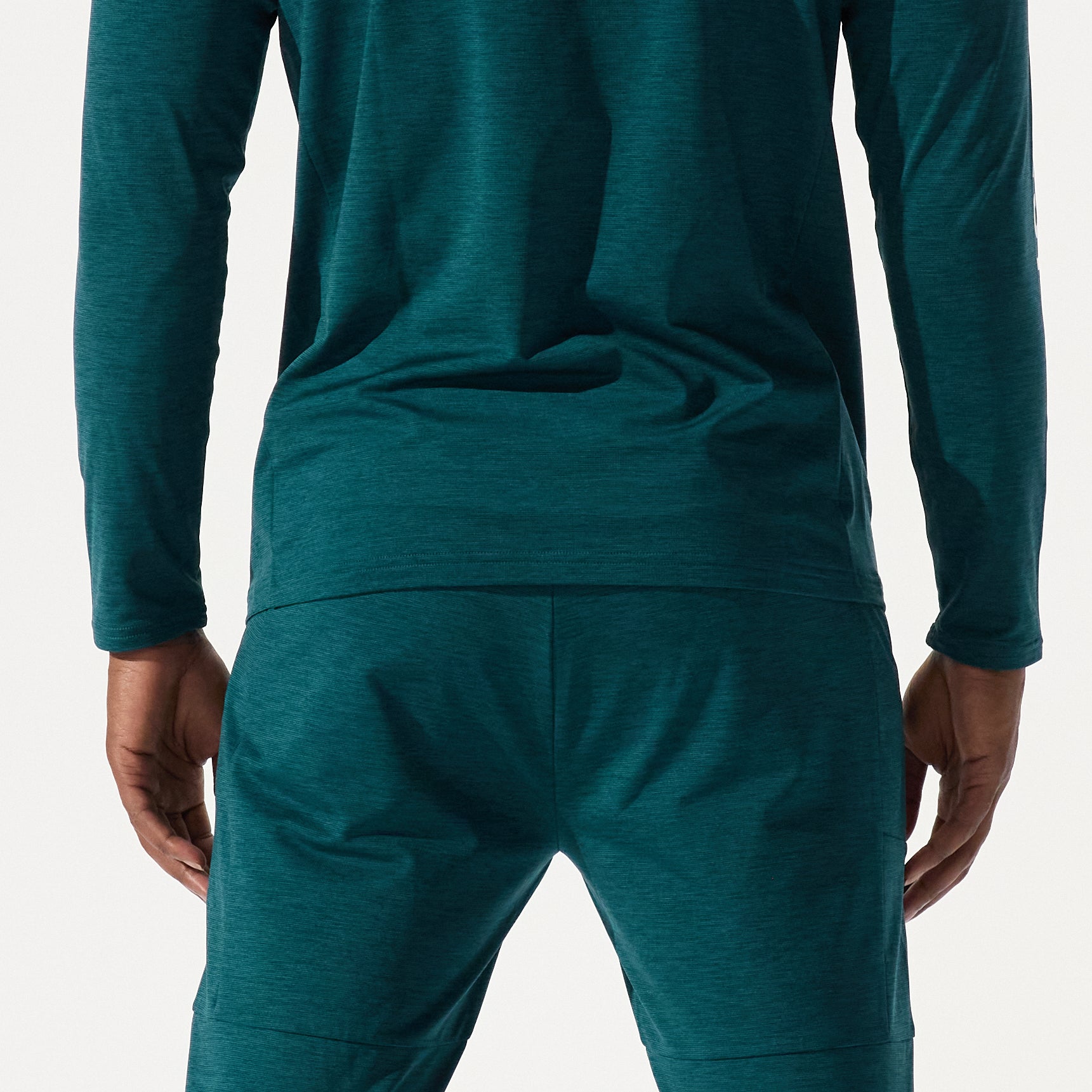 Model, from the back, wearing graphine crewneck and graphine basepant in atlantic deep colorway on a white background.