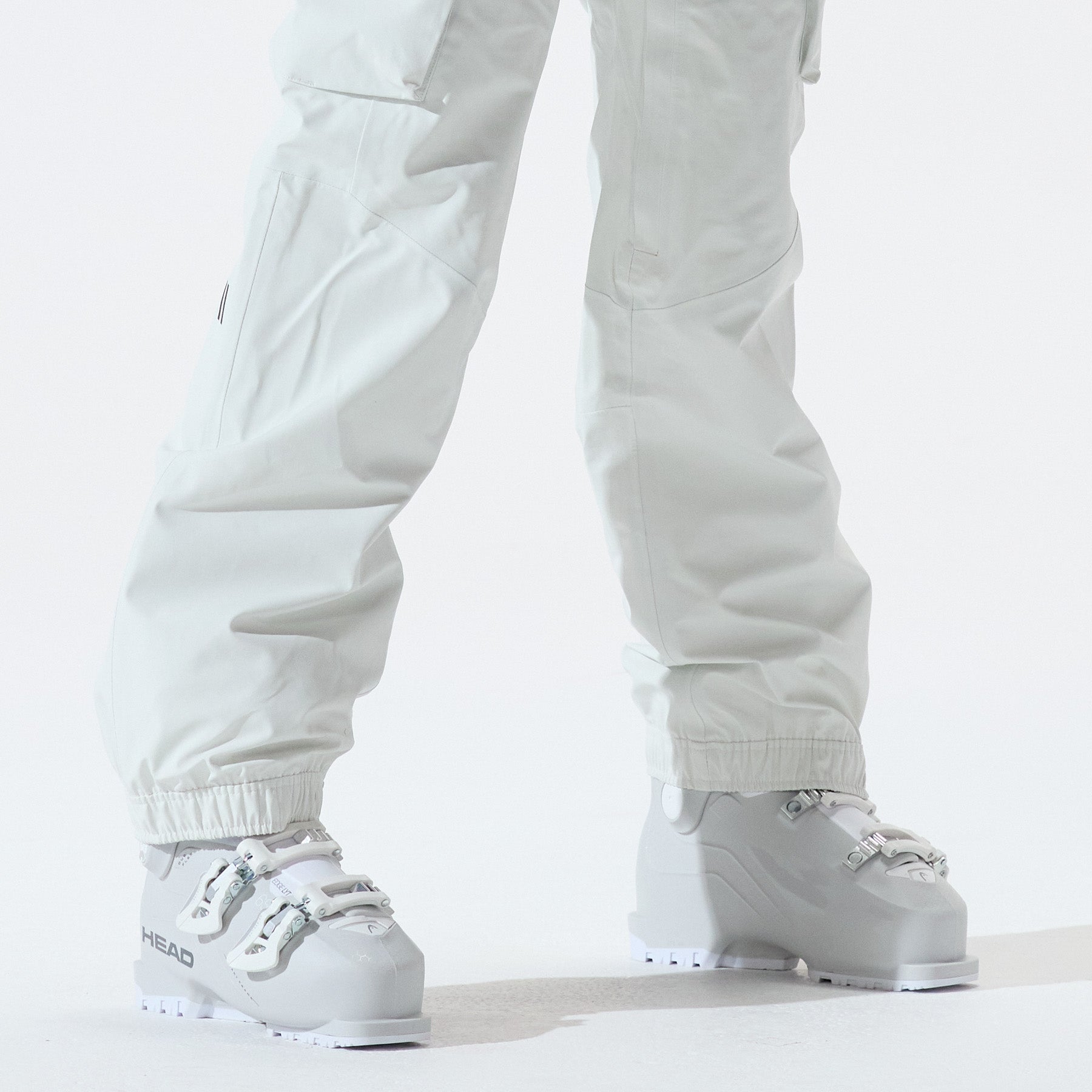 Model wearing white snow pants and white snowboots.