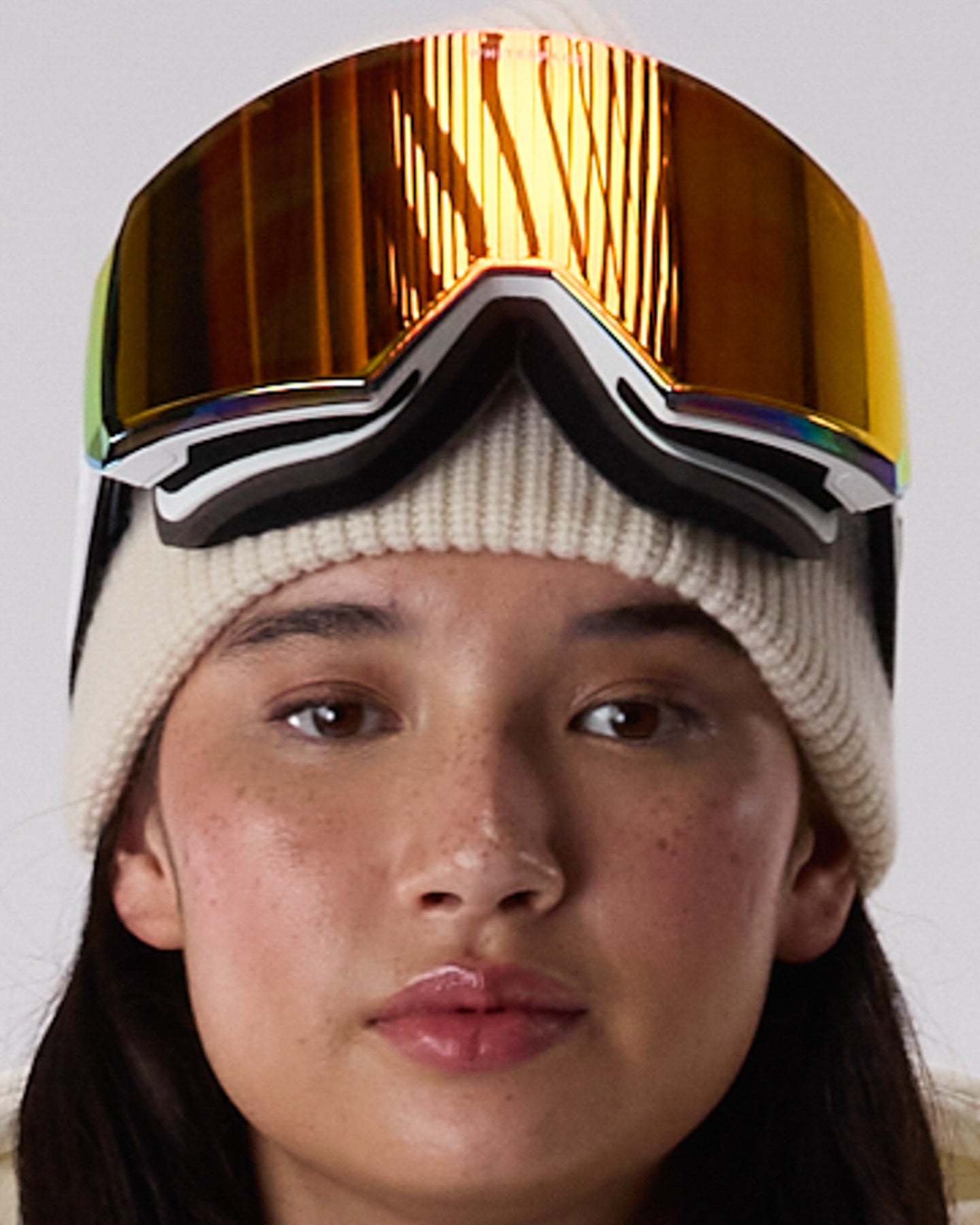 Close-up of a person wearing WHITESPACE MD Icon goggles in white over a cream beanie, on a white background.