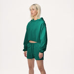 Model wearing WHITESPACE cropped hoodie in rainforest green and rainforest green sweatshorts, shown from the knees up, against a white background.