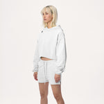 Model wearing WHITESPACE cropped hoodie in whisper white and whisper white sweatshorts, shown from the knees up, against a white background.