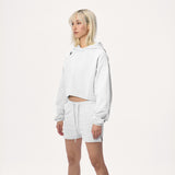 Model wearing WHITESPACE cropped hoodie in whisper white and whisper white sweatshorts, shown from the knees up, against a white background.