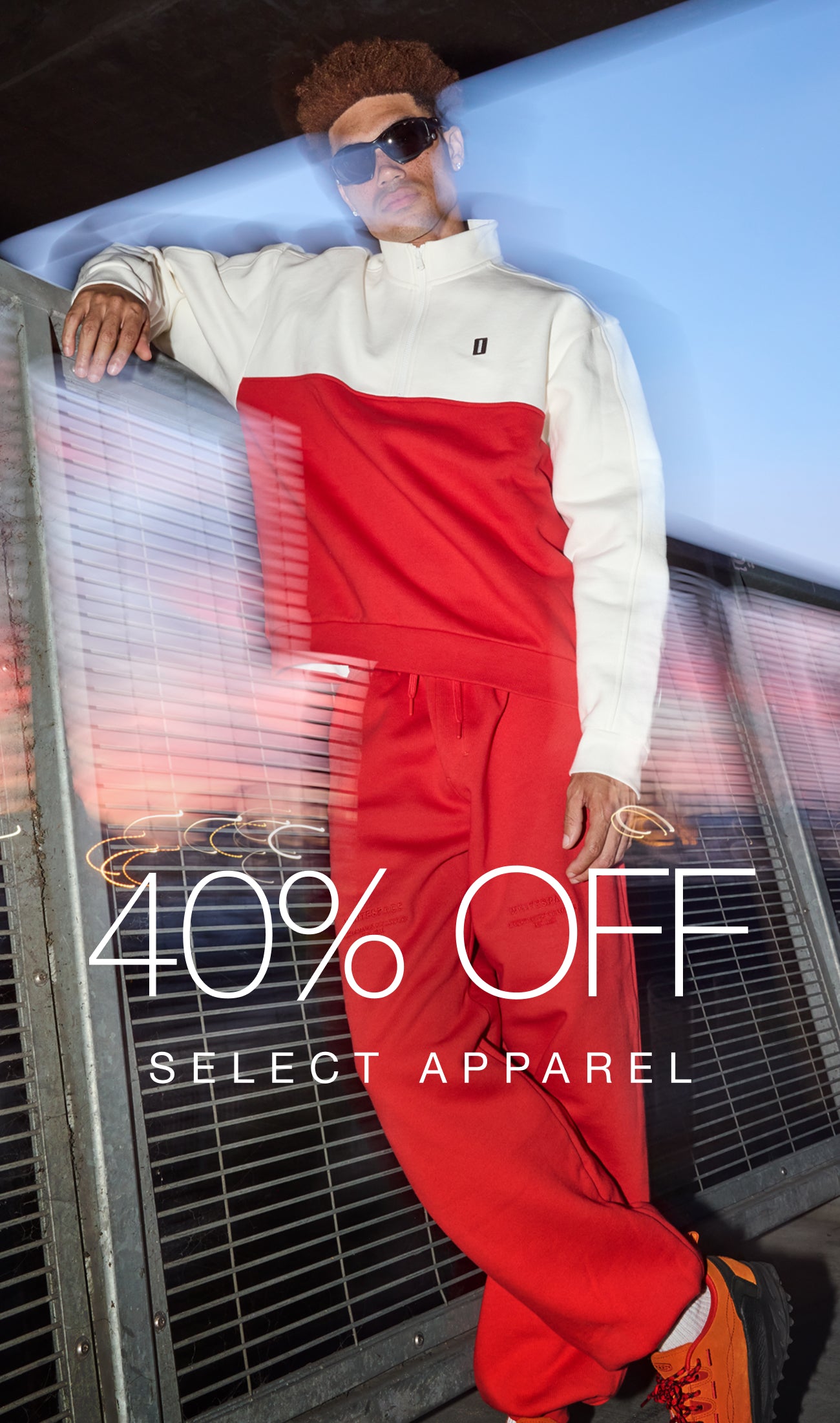 Model wearing the WHITESPACE Quarter Zip and Travel Pant in Aura Orange beside the promotional message 40% OFF SELECT APPAREL