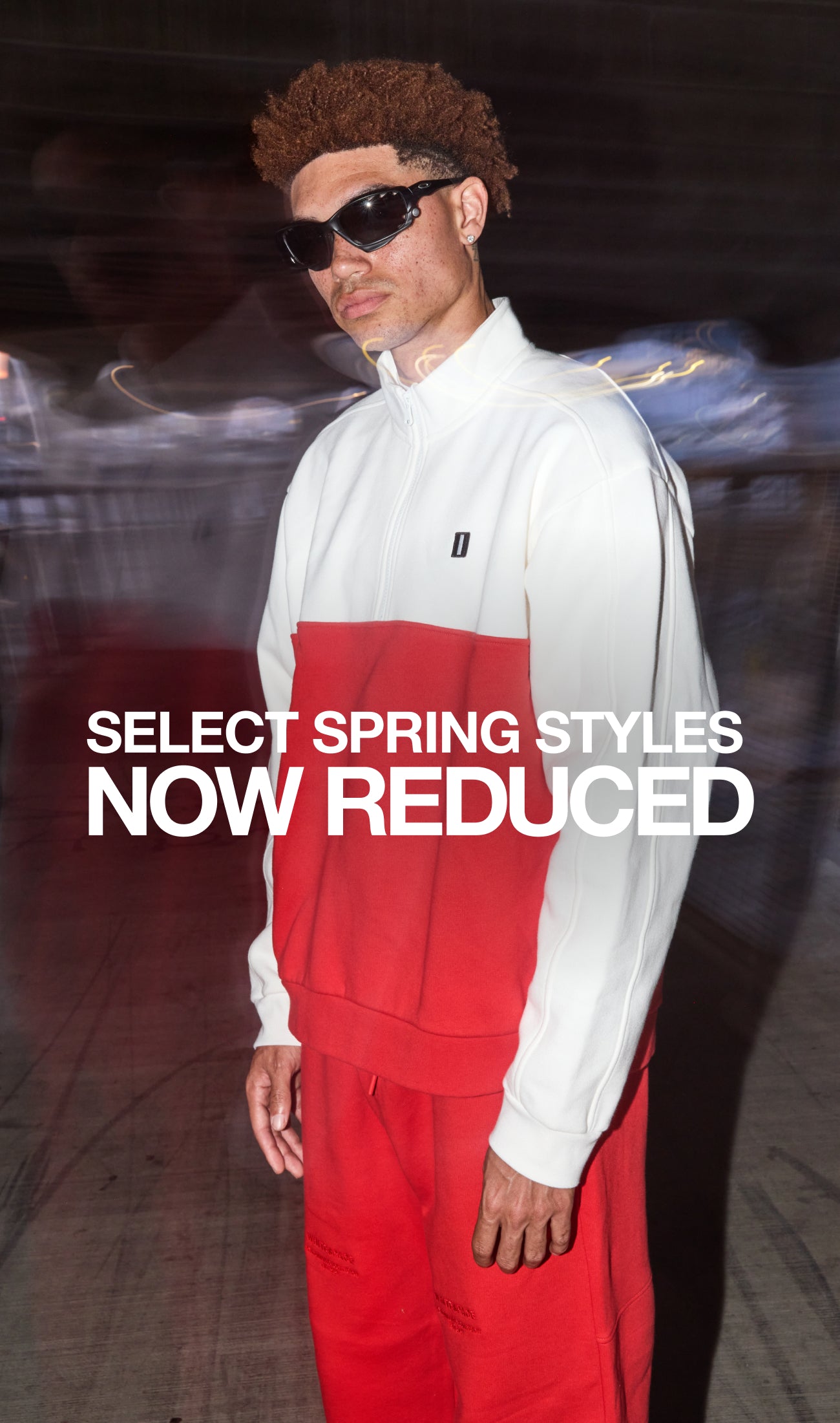 Model wearing the WHITESPACE Quarter Zip in Whisper White / Aura Orange beside the promotional message SELECT SPRING STYLES NOW REDUCED
