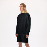 Model wearing WHITEPACE Fleece Crewneck in black with black fleece shorts shown from the knees up, against a white background.