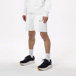 Model wearing WHITESPACE quarter zip sweatshirt in whisper white and whisper white fleece shorts with black shoes and white socks, shown from mid chest and down