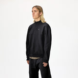 Model wearing WHITESPACE quarter zip sweatshirt in black and black WHITESPACE travel pants shown from knees up, against a white background