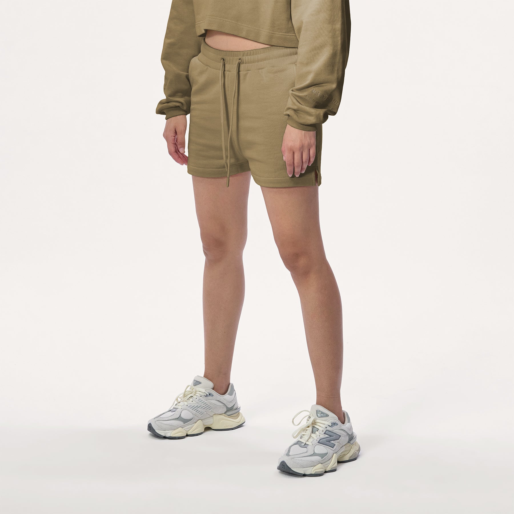 Model wearing WHITESPACE cropped hoodie in desert taupe and desert taupe sweatshorts with white shoes, shown from mid chest and down.