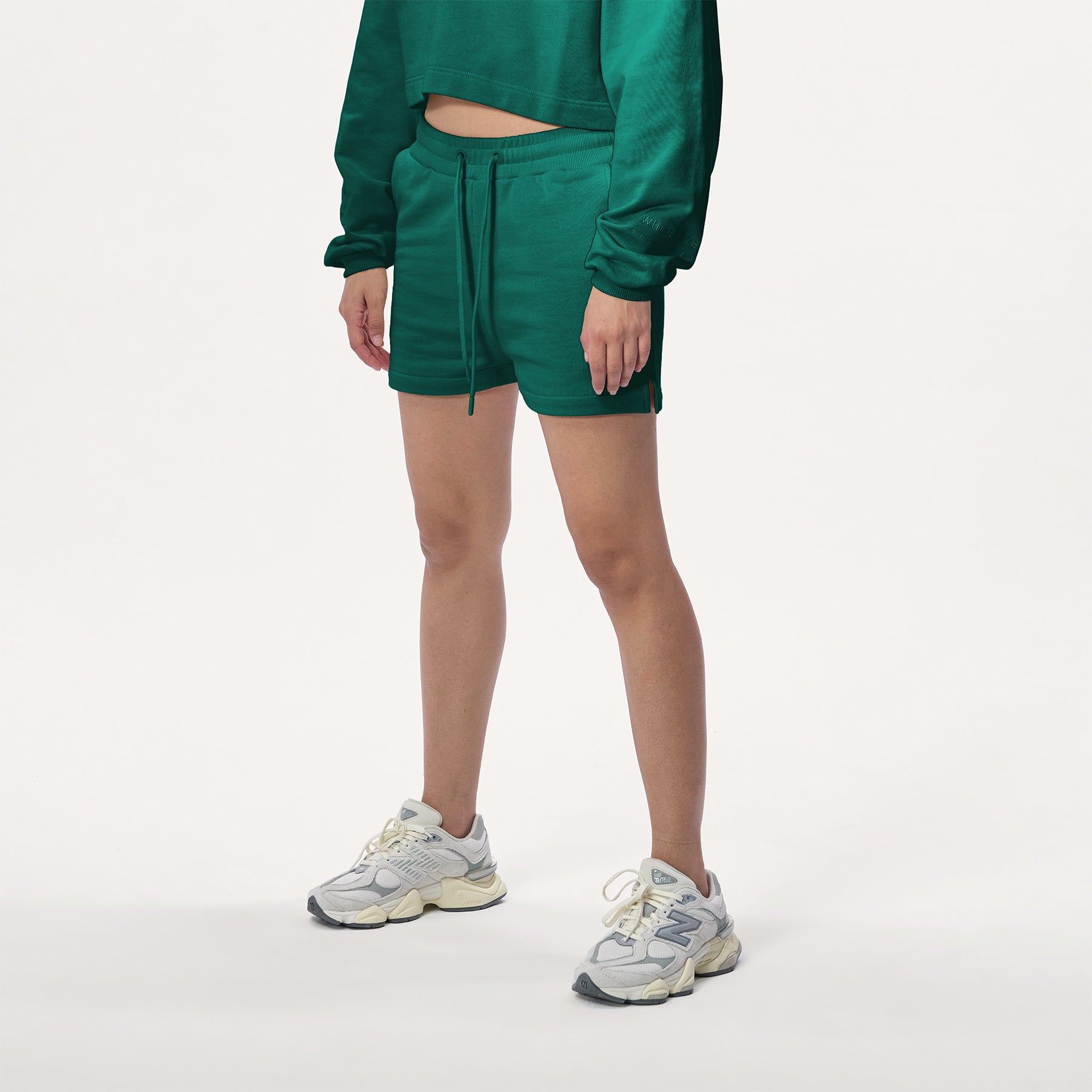 Model wearing WHITESPACE cropped hoodie in rainforest green and rainforest green sweatshorts with white shoes, shown from mid chest and down.