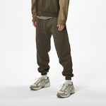 Model wearing WHITESPACE quarter zip sweatshirt in slate black/desert taupe and slate black WHITESPACE travel pants with light shoes and white socks, shown from mid chest and down