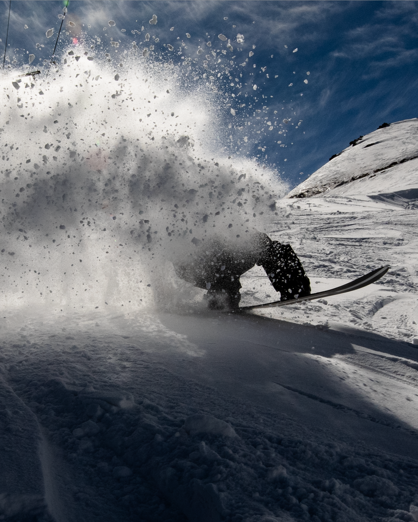 Snowboarder spraying snow on a WHITESPACE snowboard.