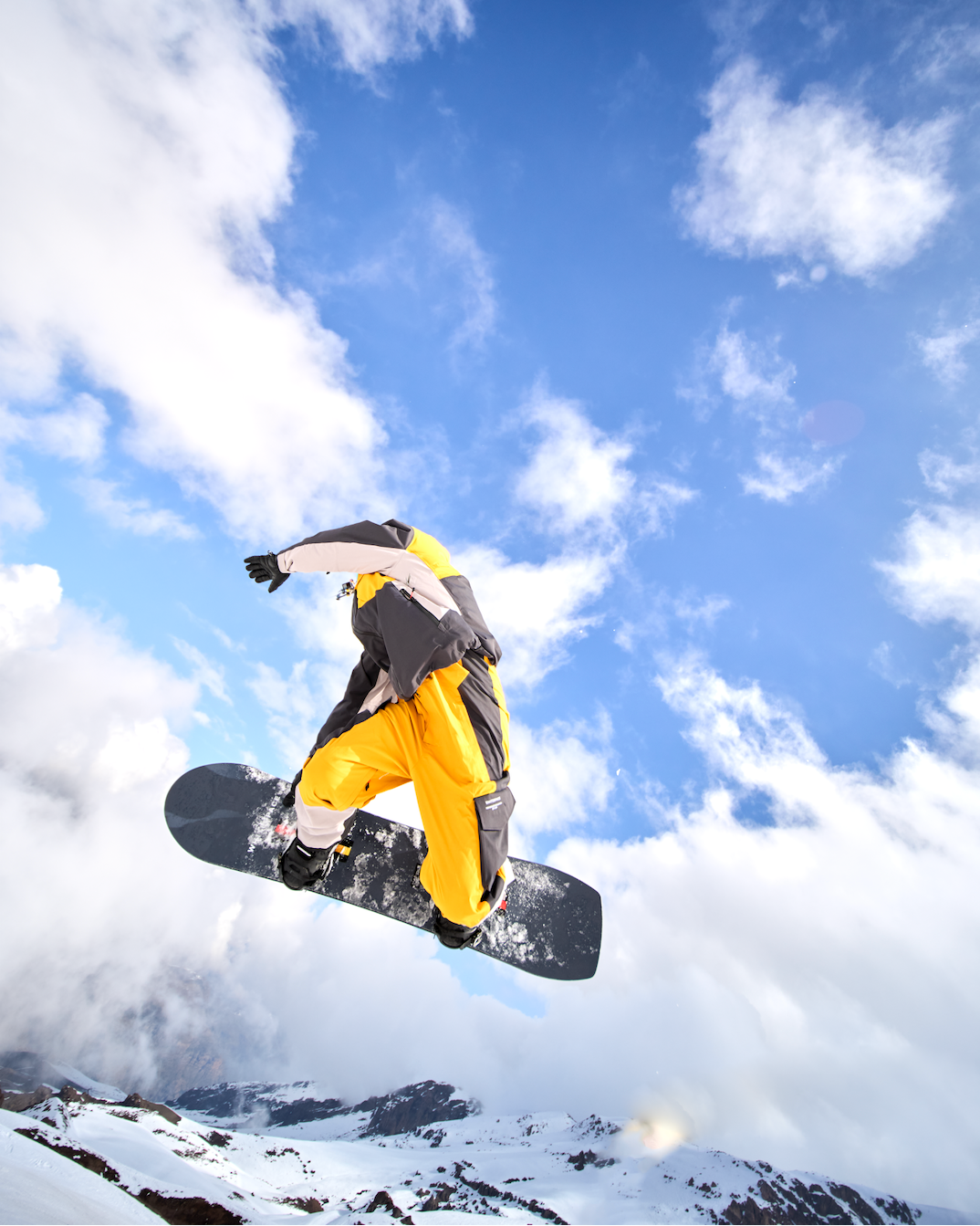 Pro snowboarder wearing the WHITESPACE 2L Insulated Cargo Kit performing an aerial on the WHITESPACE MAAX board.