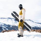 Person standing on a snowy mountain holding a WhiteSpace snowboard and wearing 2L Cargo Insulated Jacket in Khaki and Green Khaki and pants.