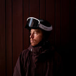 Shaun White leaning against a wall looking to his side wearing AMF Riding Cargo Jacket in Dark Mauve Purple and Dual Tone Goggles in Back and White.