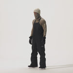 Video of model wearing 2L Insulated Cargo Bib Pants in Black over a beige shirt and gaiter, on a white background.